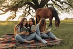 Junge Frauen sitzen auf einer Picknickdecke und lesen in Büchern.