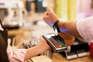 Mann zahlt mit Uhr und benutzt kein Bargeld mehr.