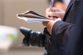 Ein Journalist mit Kamera, Stift und Block,