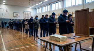 Eine lange Schlange von wartenden Wählern in Winterkleidung steht in einer Turnhalle
