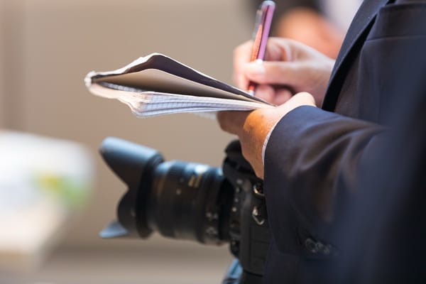 Ein Journalist mit Kamera, Stift und Block,